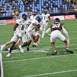 Holding the ball up high and tight Barrow lowers his shoulder for the impact.