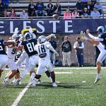 The hand was up in the last photo, but downward in this photo, showing the ball actually blocked in mid-air.  There are a lot of white jerseys in the picture.