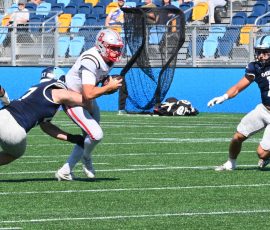 URI captain Case Mankins brings down Brown quarterback James Murphy as Dane Picariello #16 closes in during a first quarter sack — one of several pressures URI's defense applied to the FCS's third-ranked passer, who averaged 279.8 yards per game in 2025, during the Rams' Governor's Cup victory at Centreville Bank Stadium in Pawtucket